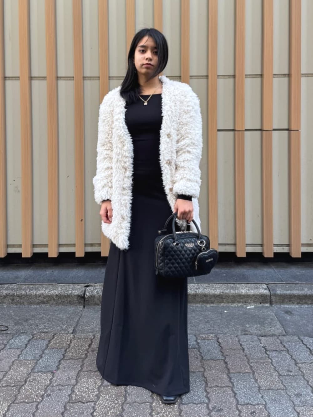 ブラック系のハンドバッグ、ブラック系のワンピース、ホワイト系のカーディガン/ボレロを着用したレディースの春コーディネートの2枚目の写真