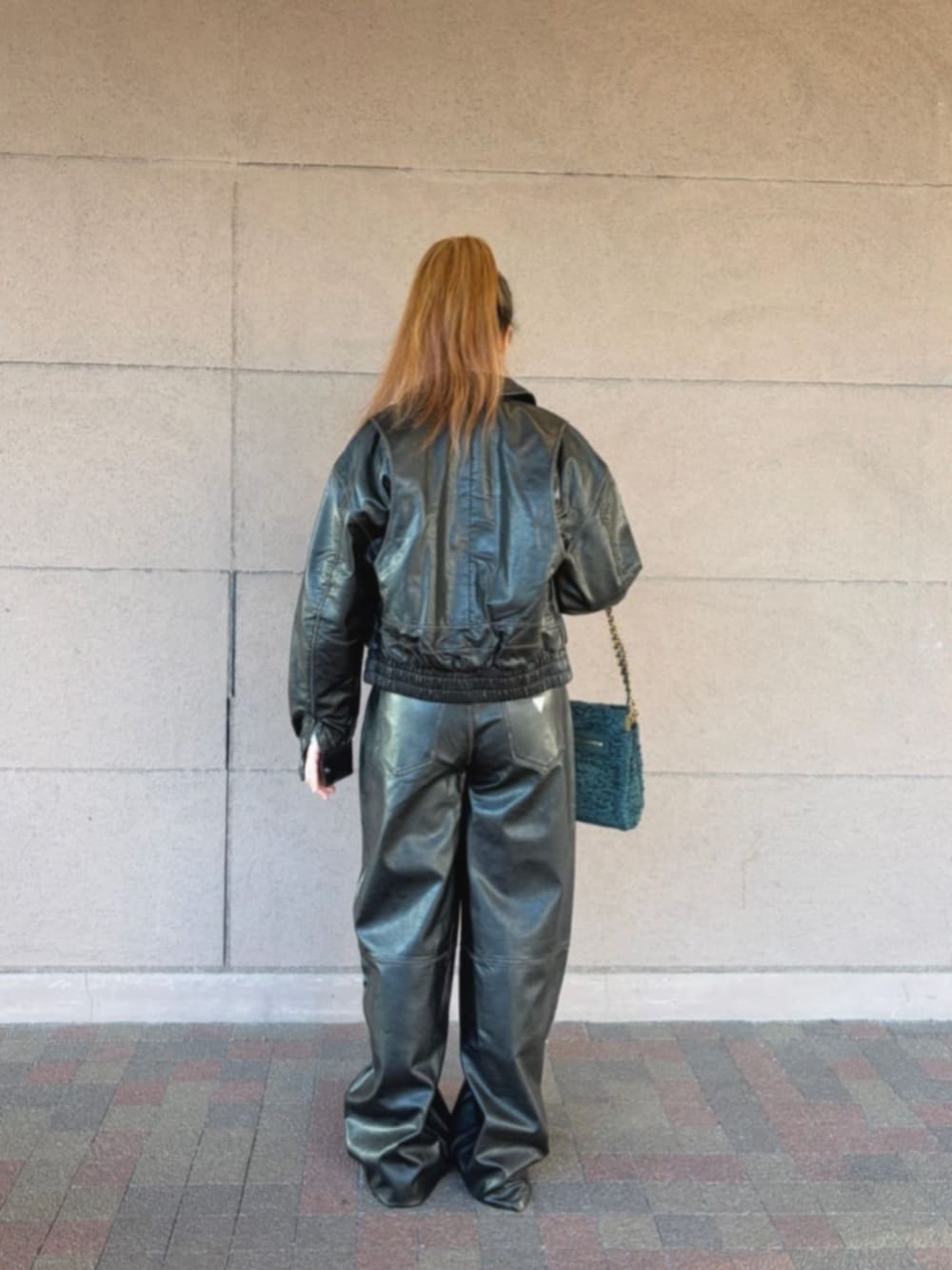 グリーン系のショルダーバッグ、ブラック系のその他アウター、ホワイト系のニット/セーターを着用したレディースの冬コーディネートの2枚目の写真