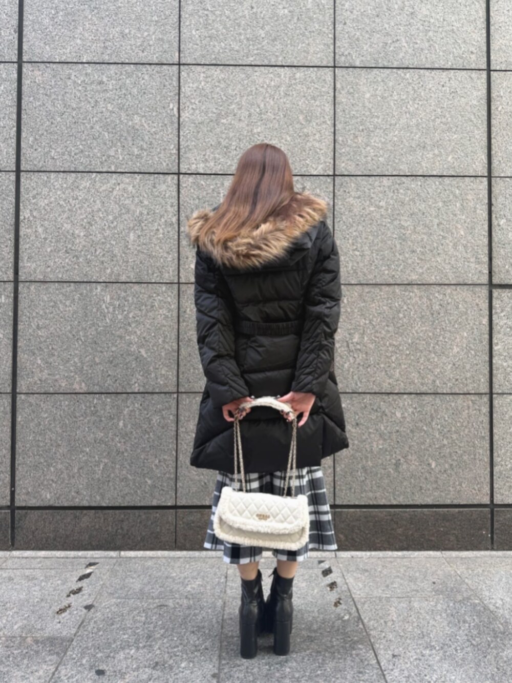 ブラック系のダウンジャケット/コート、ホワイト系のショルダーバッグ、ブラック系のワンピースを着用したレディースの冬コーディネートの3枚目の写真