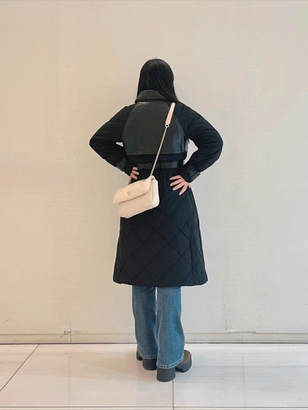 ブルー系のデニムパンツ、ホワイト系のニット/セーター、ホワイト系のショルダーバッグを着用したレディースの秋コーディネートの2枚目の写真