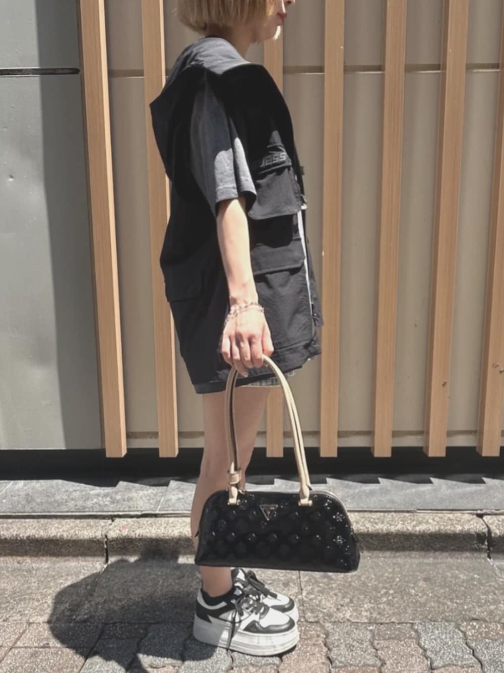 ブラック系のショルダーバッグ、グレー系のTシャツ/カットソー、ブルー系のデニムパンツを着用したレディースの夏コーディネートの3枚目の写真