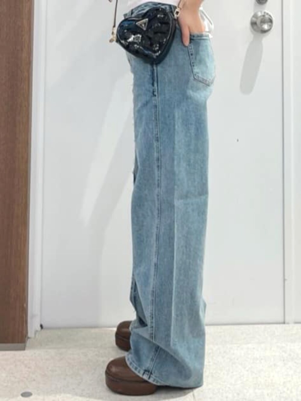 ブラック系のショルダーバッグ、ブルー系のデニムパンツ、ピンク系のTシャツ/カットソーを着用したレディースの夏コーディネートの5枚目の写真