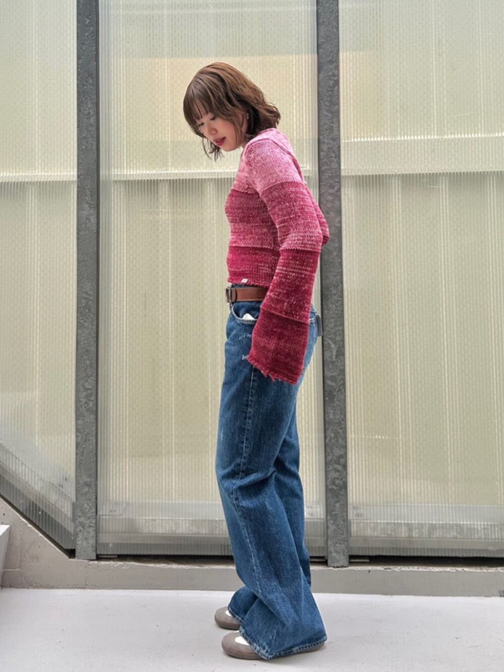 レッド系のニット/セーター、ブルー系のデニムパンツを着用したレディースの秋コーディネートの3枚目の写真