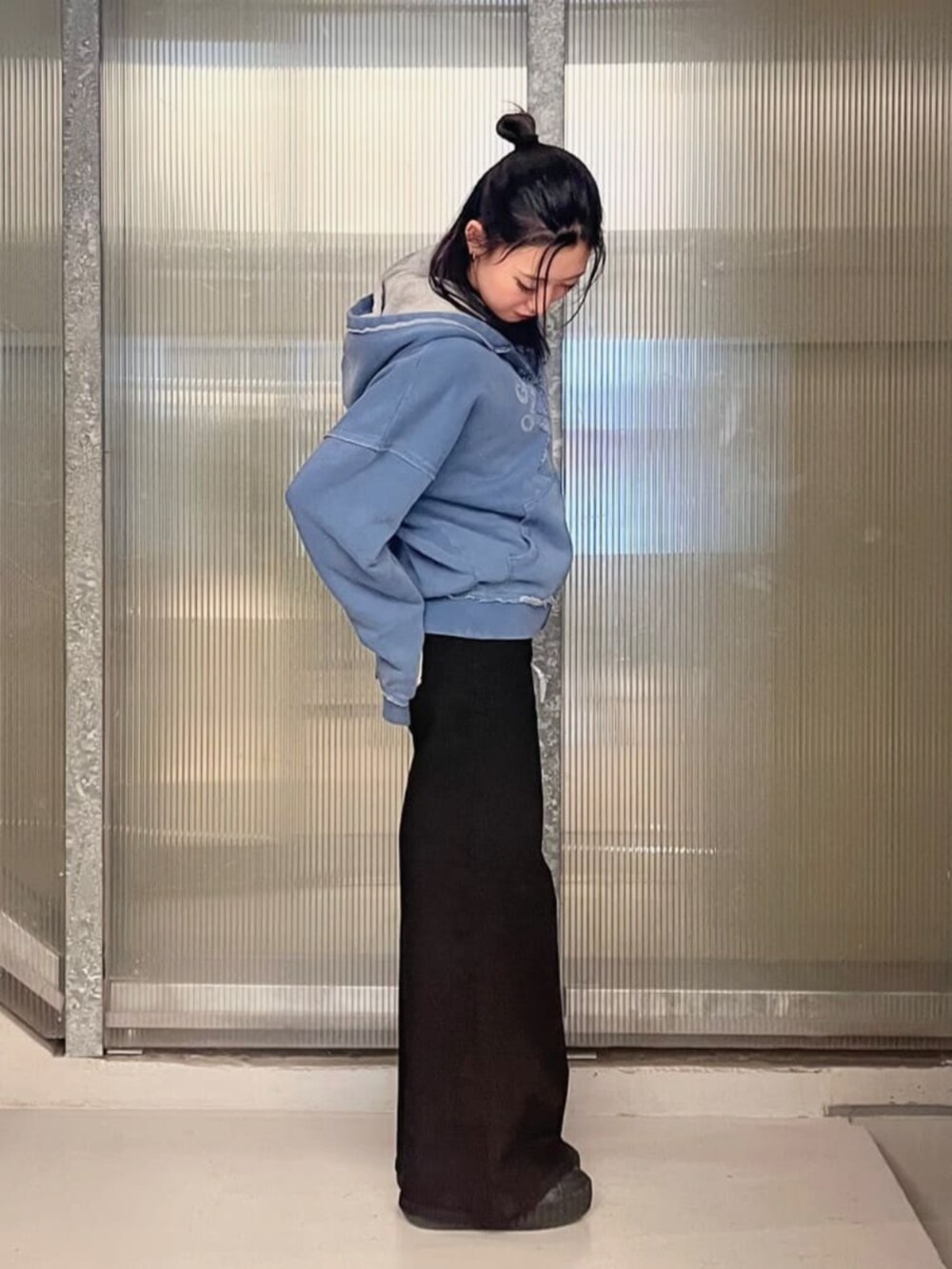 グレー系のパーカー、ブラック系のデニムパンツ、ブルー系のパーカーを着用したレディースの秋コーディネートの3枚目の写真