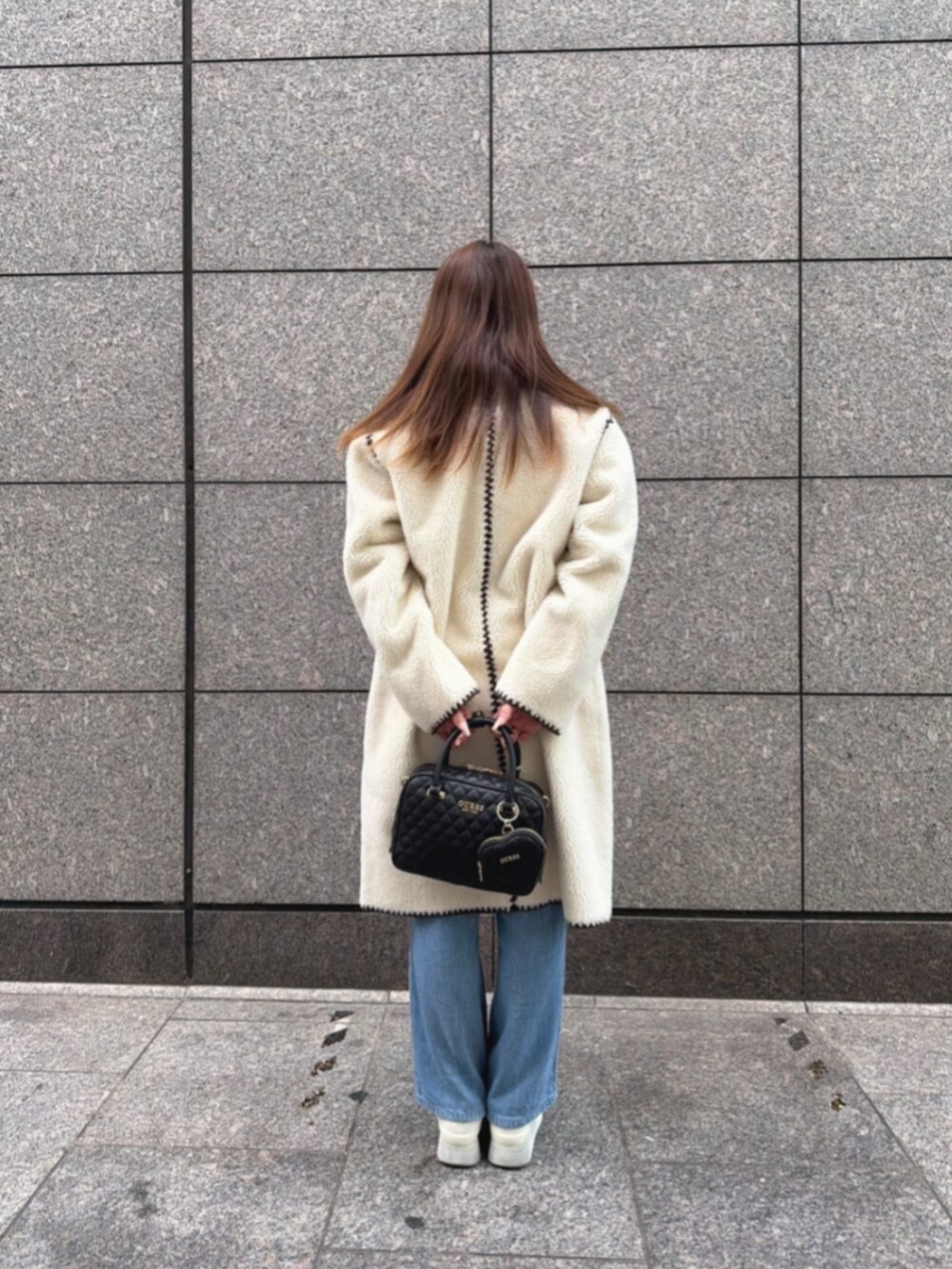 ブルー系のデニムパンツ、ブルー系のニット/セーター、ホワイト系のノーカラージャケットを着用したレディースの冬コーディネートの2枚目の写真