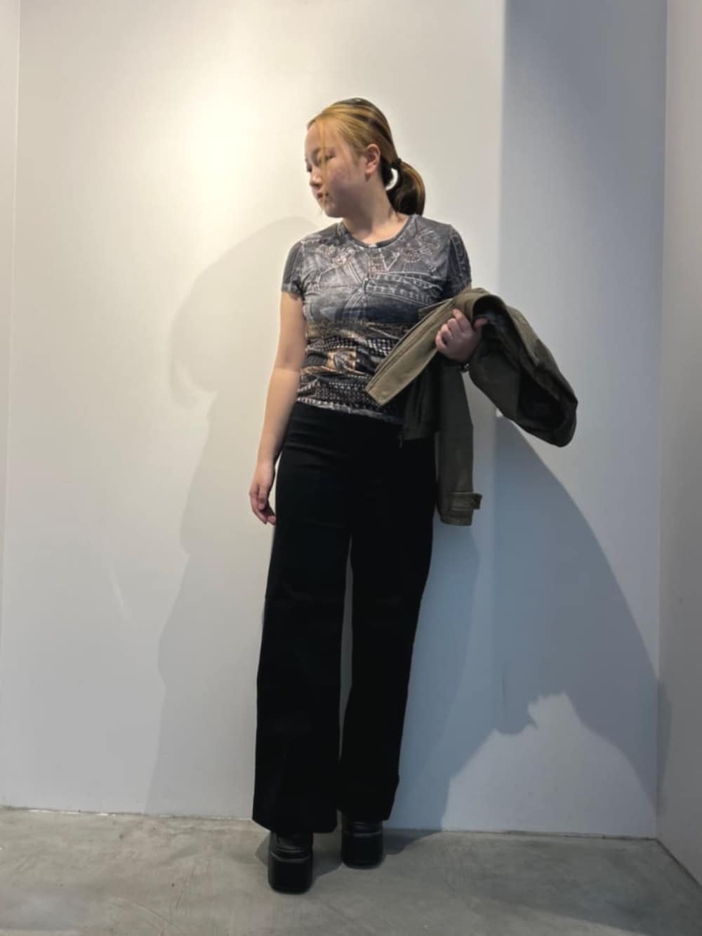 ブラック系のデニムパンツ、ブラック系のTシャツ/カットソー、グリーン系のミリタリージャケットを着用したレディースの春コーディネートの2枚目の写真