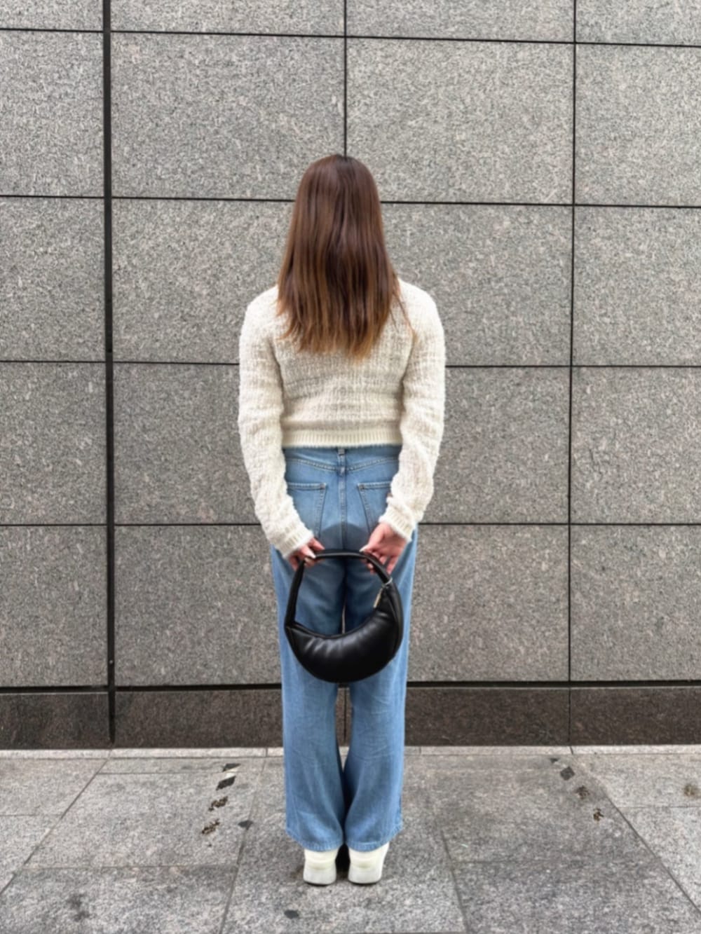 ブルー系のデニムパンツ、ブラック系のショルダーバッグ、ホワイト系のカーディガン/ボレロを着用したレディースの冬コーディネートの2枚目の写真