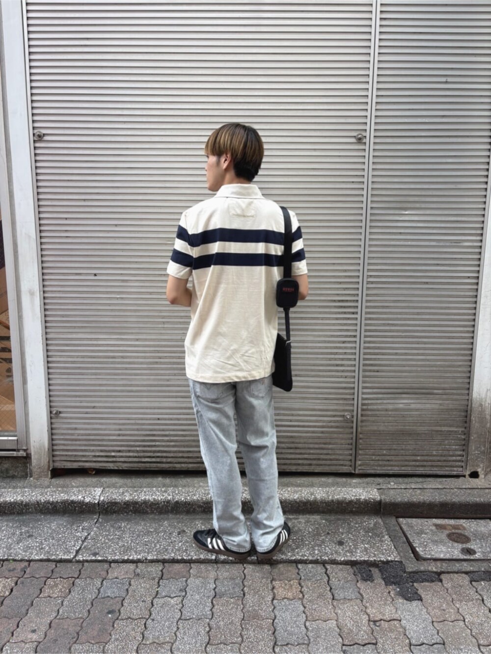 グレー系のデニムパンツ、ホワイト系のポロシャツを着用したメンズの秋コーディネートの2枚目の写真