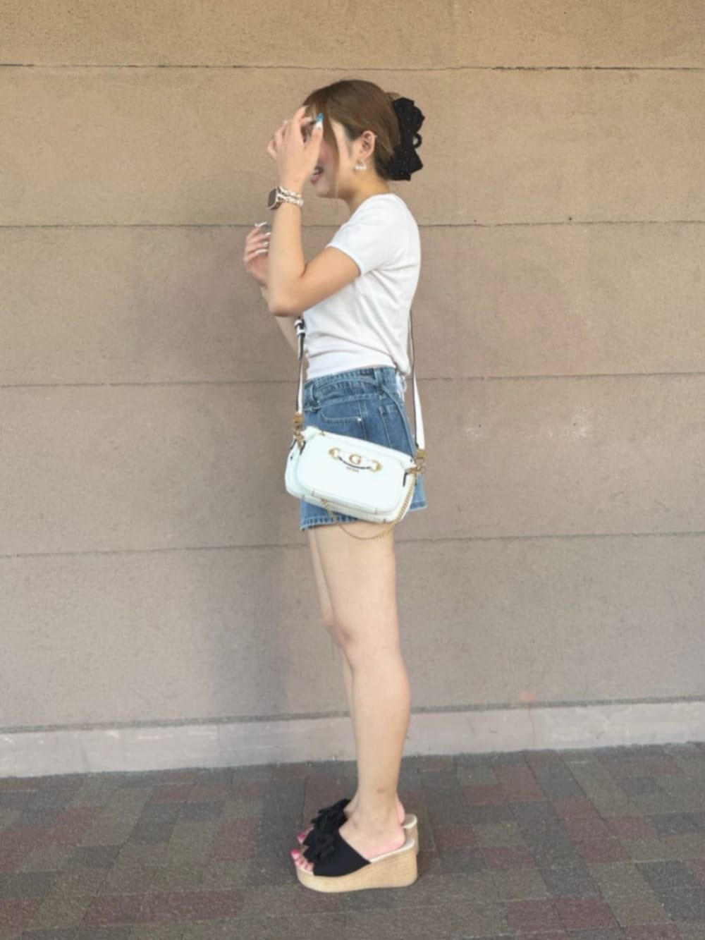 ホワイト系のショルダーバッグ、ブルー系のデニムパンツ、ピンク系のTシャツ/カットソーを着用したレディースの秋コーディネートの3枚目の写真