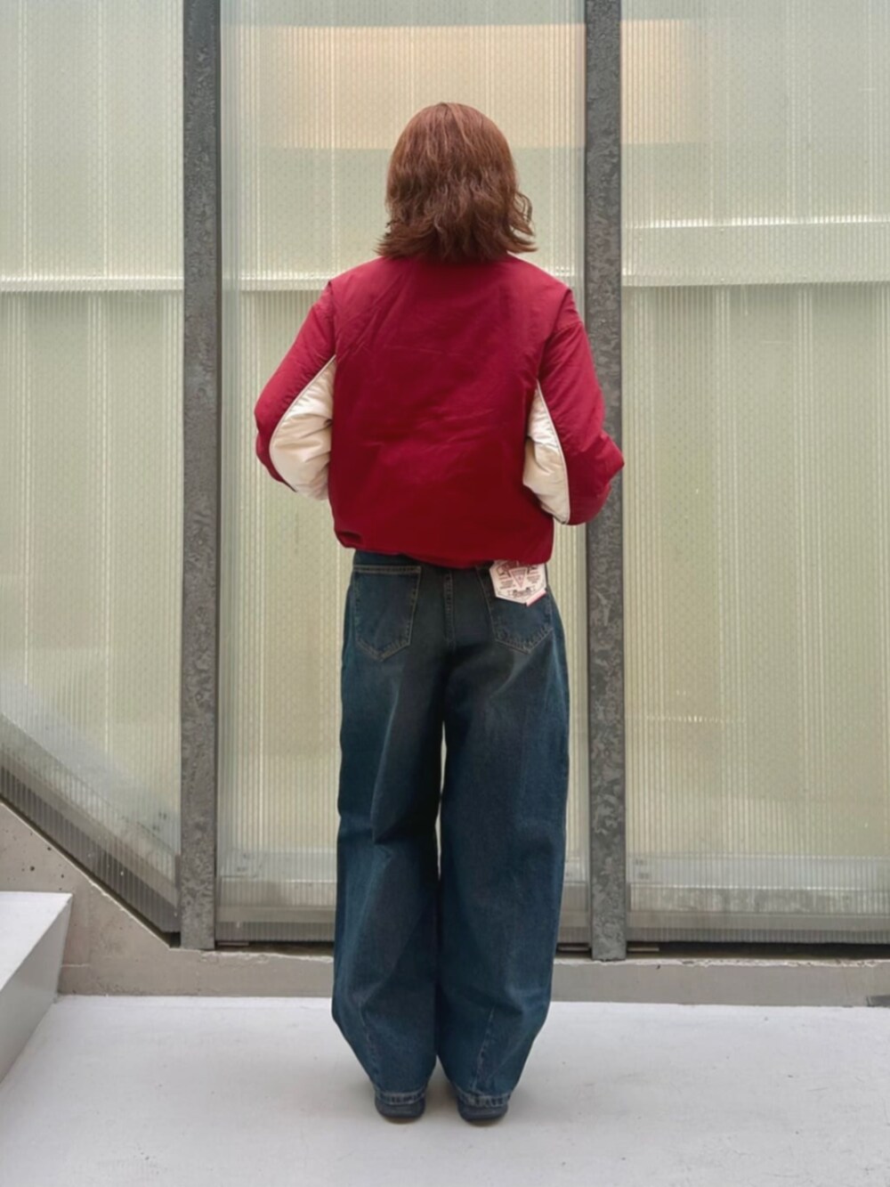 ブルー系のデニムパンツ、レッド系のナイロンジャケットを着用したレディースの冬コーディネートの2枚目の写真