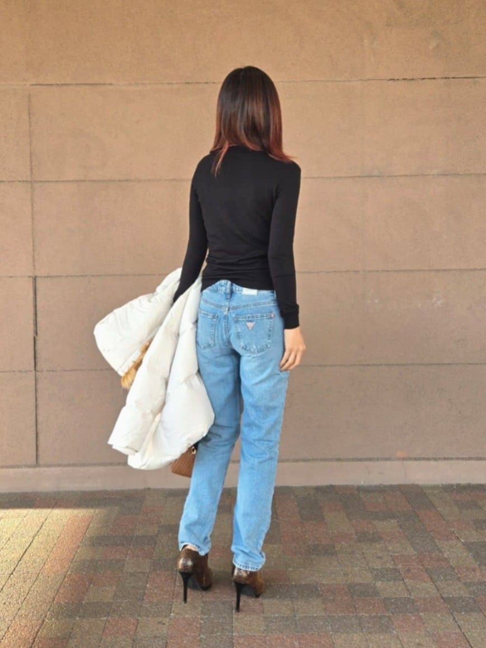 ブルー系のデニムパンツ、ブラック系のTシャツ/カットソー、ブラウン系のショルダーバッグを着用したレディースの冬コーディネートの5枚目の写真