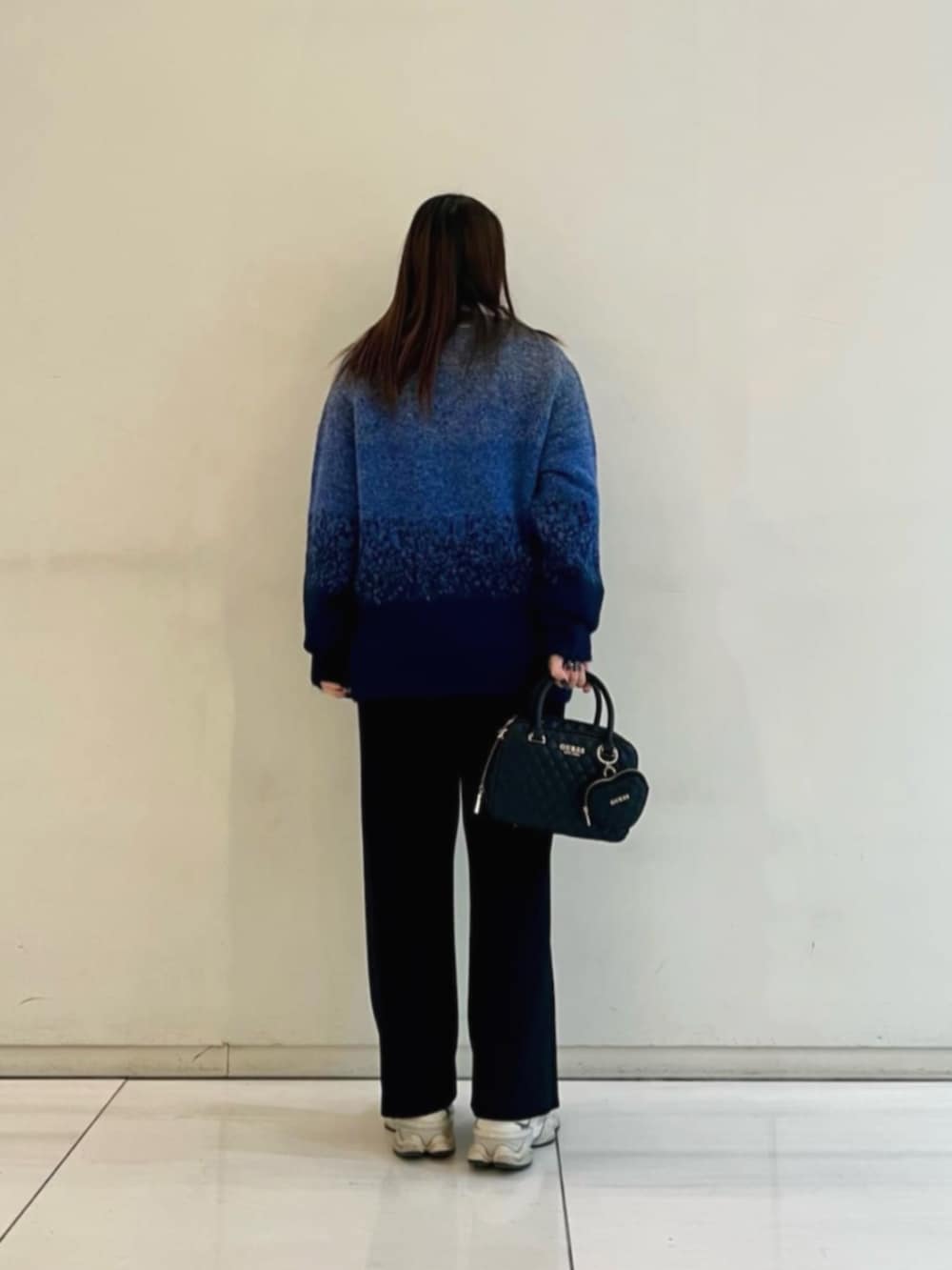 ブラック系のハンドバッグ、ブルー系のポロシャツ、ブルー系のニット/セーターを着用したレディースの冬コーディネートの2枚目の写真