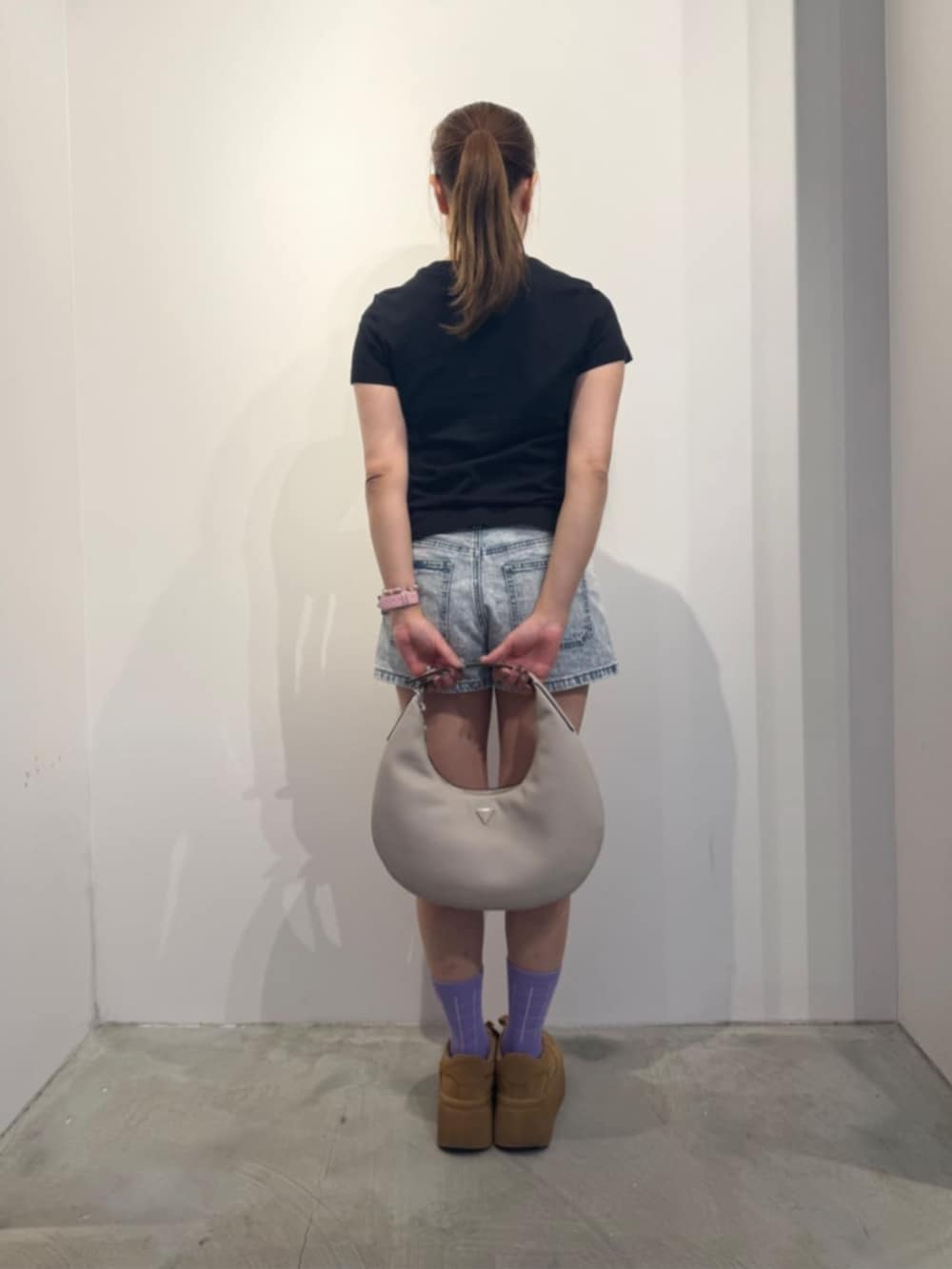 ブルー系のデニムパンツ、ベージュ系のハンドバッグ、ブラック系のTシャツ/カットソーを着用したレディースの冬コーディネートの2枚目の写真