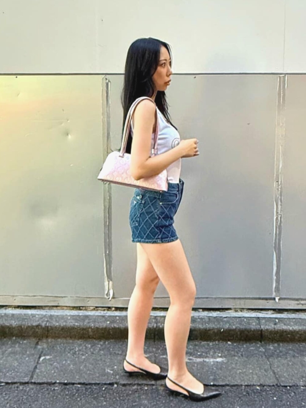 ピンク系のショルダーバッグ、ブルー系のデニムパンツ、ホワイト系のタンクトップを着用したレディースの夏コーディネートの3枚目の写真
