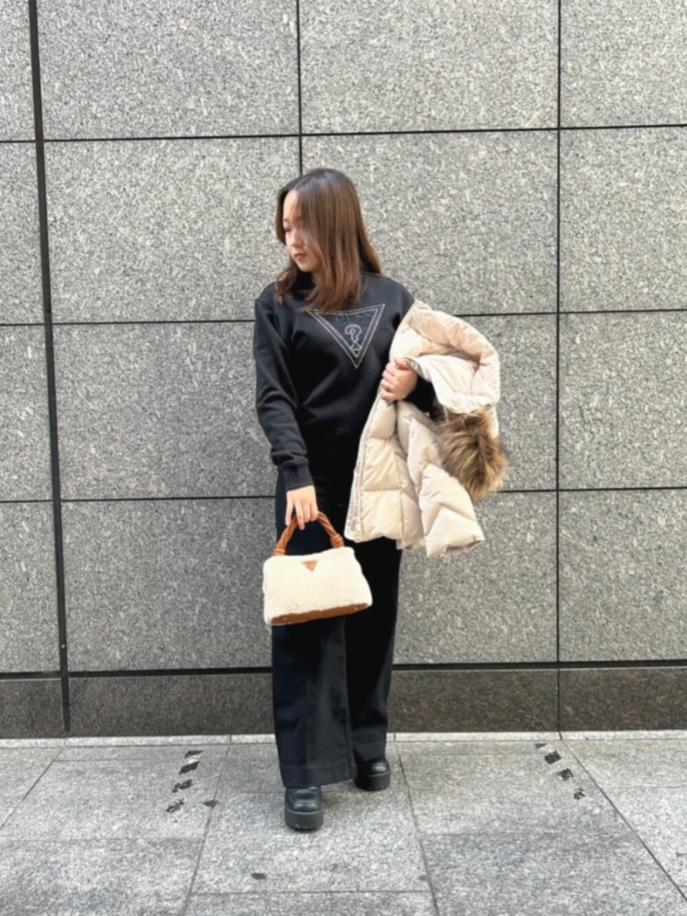 ブラック系のデニムパンツ、ベージュ系のダウンジャケット/コート、イエロー系のショルダーバッグを着用したレディースの冬コーディネートの4枚目の写真