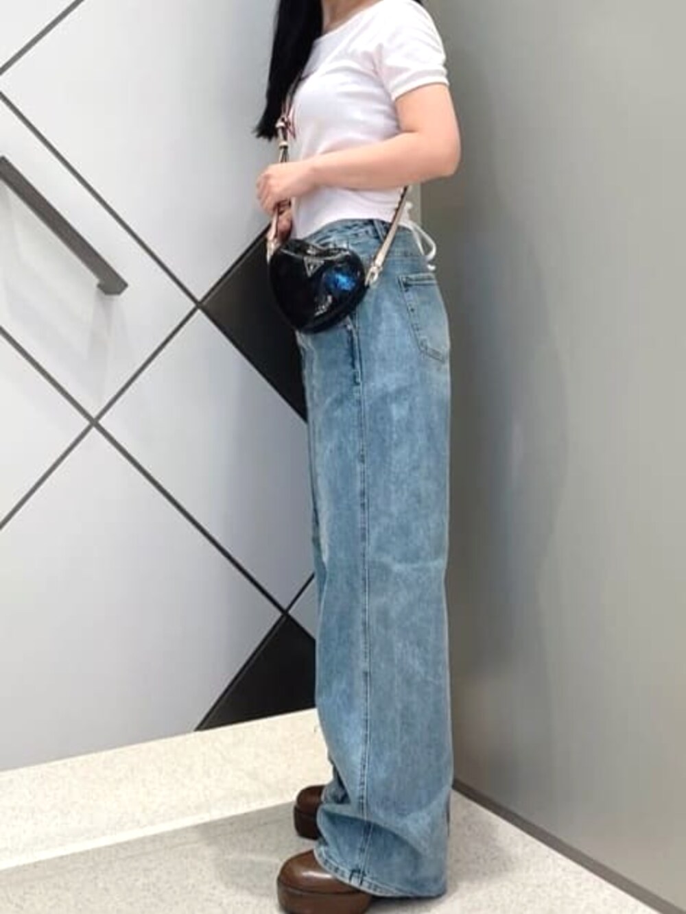 ブラック系のショルダーバッグ、ブルー系のデニムパンツ、ピンク系のTシャツ/カットソーを着用したレディースの夏コーディネートの3枚目の写真