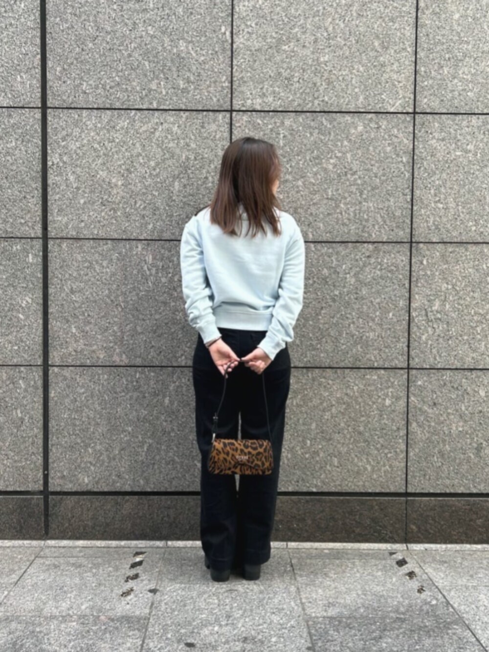 ブラック系のデニムパンツ、ブルー系のスウェット、その他のハンドバッグを着用したレディースの冬コーディネートの2枚目の写真