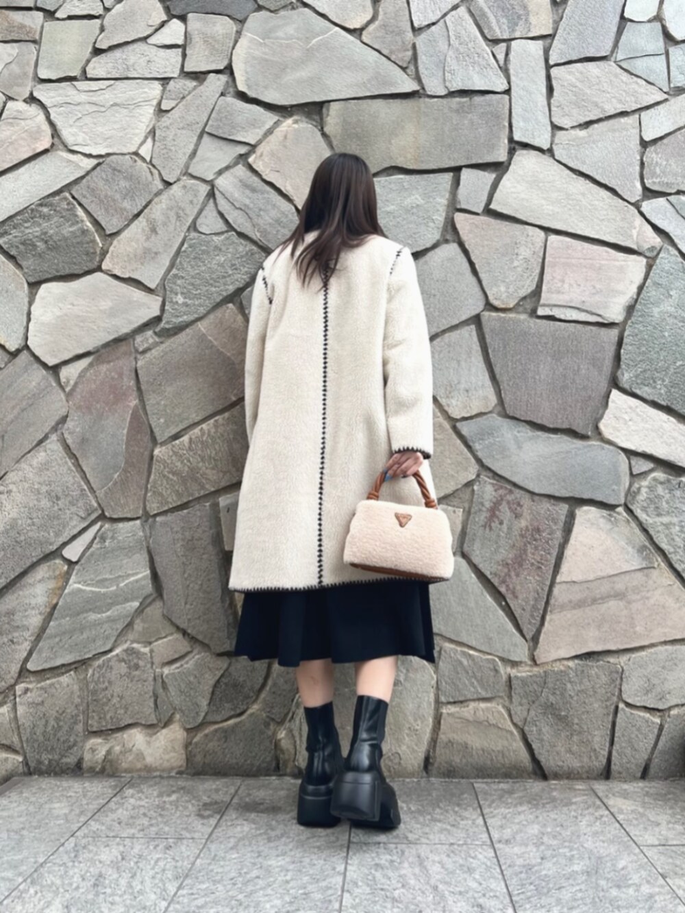 ブラック系のワンピース、ホワイト系のノーカラージャケット、イエロー系のショルダーバッグを着用したレディースの冬コーディネートの2枚目の写真