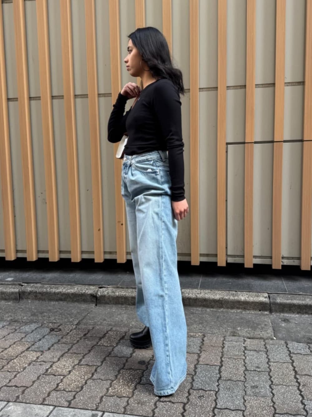 ブルー系のデニムパンツ、ブラック系のTシャツ/カットソー、イエロー系のショルダーバッグを着用したレディースの春コーディネートの3枚目の写真