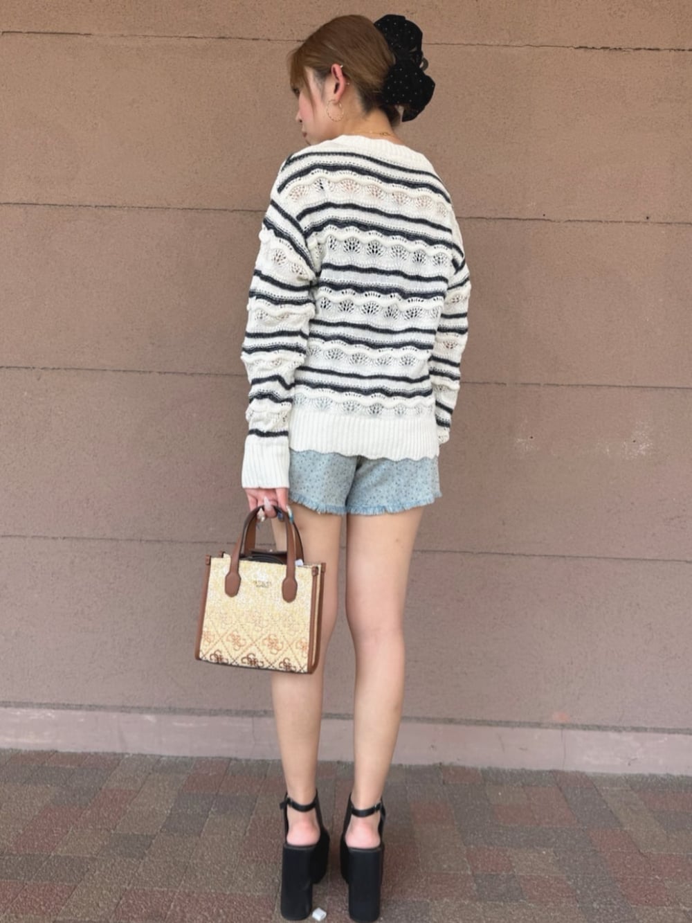 ホワイト系のニット/セーター、ブラウン系のショルダーバッグ、ブルー系のデニムパンツを着用したレディースの夏コーディネートの2枚目の写真
