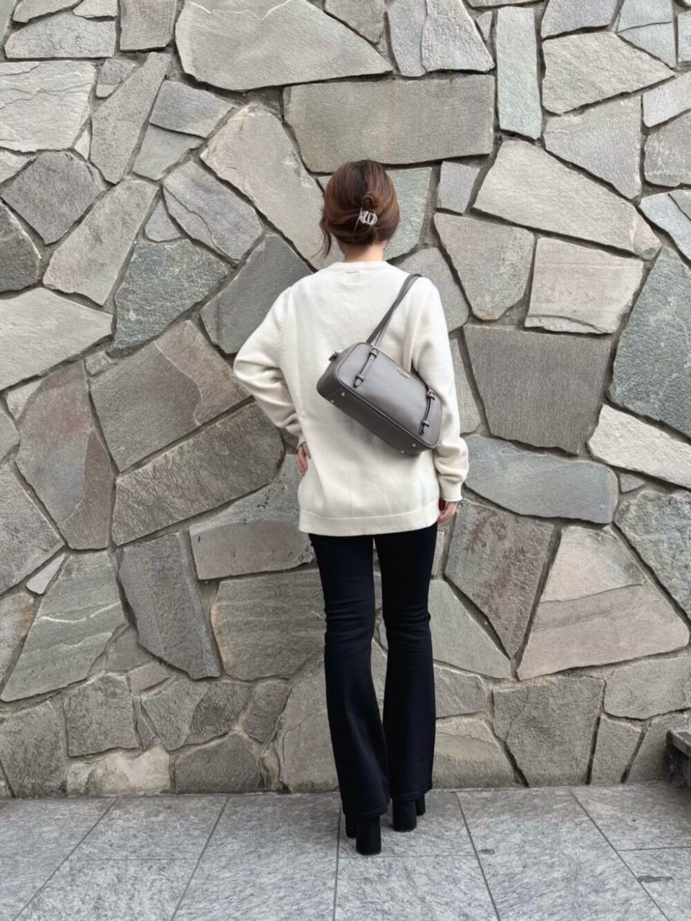 ブラック系のデニムパンツ、ベージュ系のショルダーバッグ、ホワイト系のニット/セーターを着用したレディースの秋コーディネートの2枚目の写真