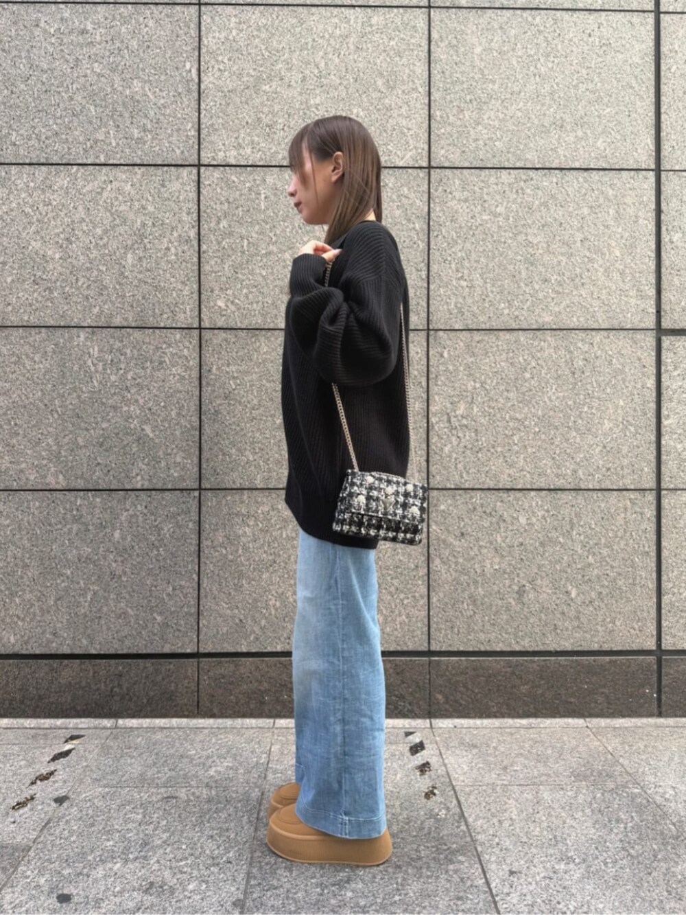 ブルー系のデニムパンツ、ブラック系のカーディガン/ボレロ、ブラック系のショルダーバッグを着用したレディースの秋コーディネートの3枚目の写真