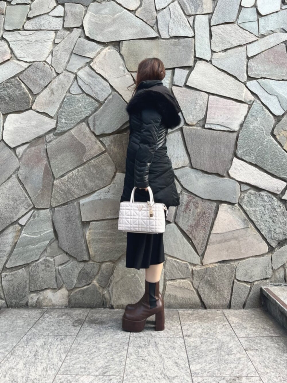 ブラック系のワンピース、ホワイト系のショルダーバッグ、ブラック系のダウンジャケット/コートを着用したレディースの秋コーディネートの3枚目の写真