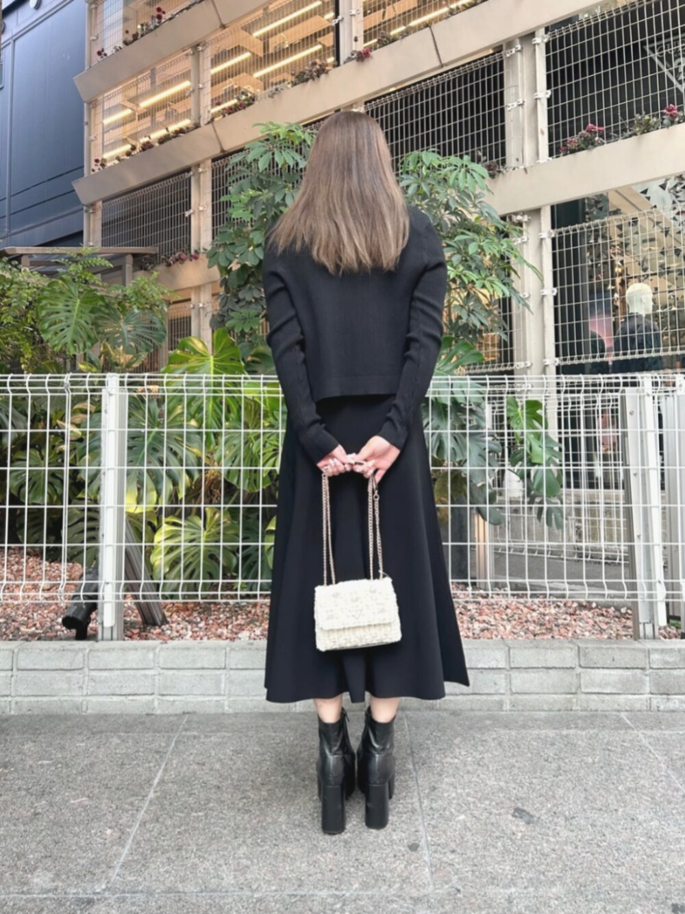 ブラック系のワンピース、ブラック系のカーディガン/ボレロ、ホワイト系のショルダーバッグを着用したレディースの秋コーディネートの2枚目の写真