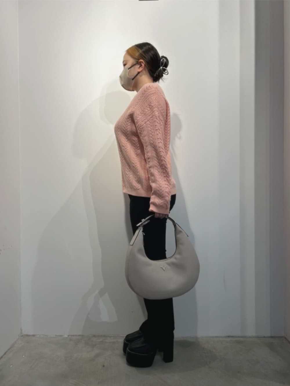 ブラック系のデニムパンツ、ベージュ系のハンドバッグ、ピンク系のニット/セーターを着用したレディースの冬コーディネートの3枚目の写真