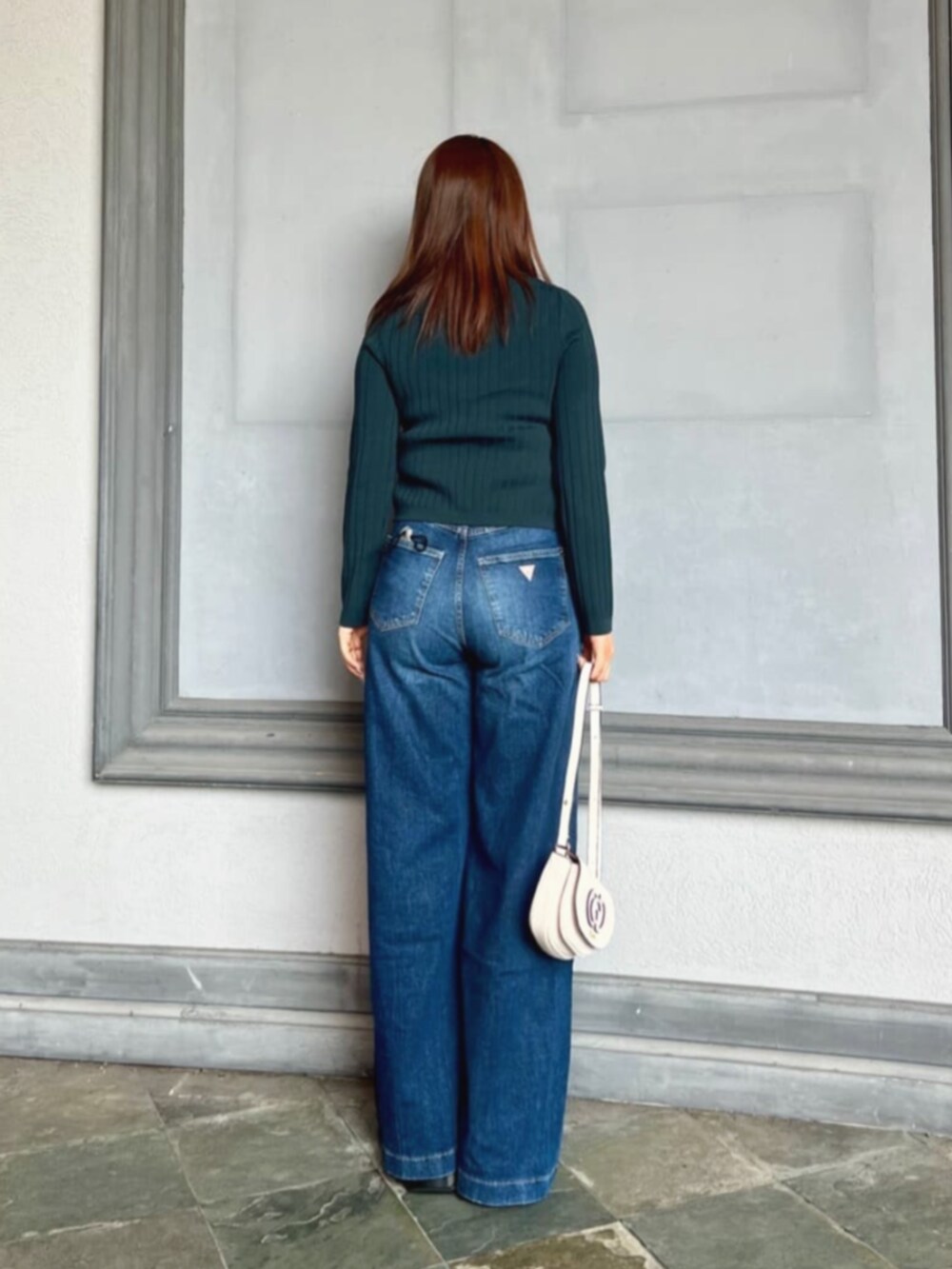 ブルー系のデニムパンツ、ホワイト系のタンクトップ、ホワイト系のショルダーバッグを着用したレディースの秋コーディネートの2枚目の写真