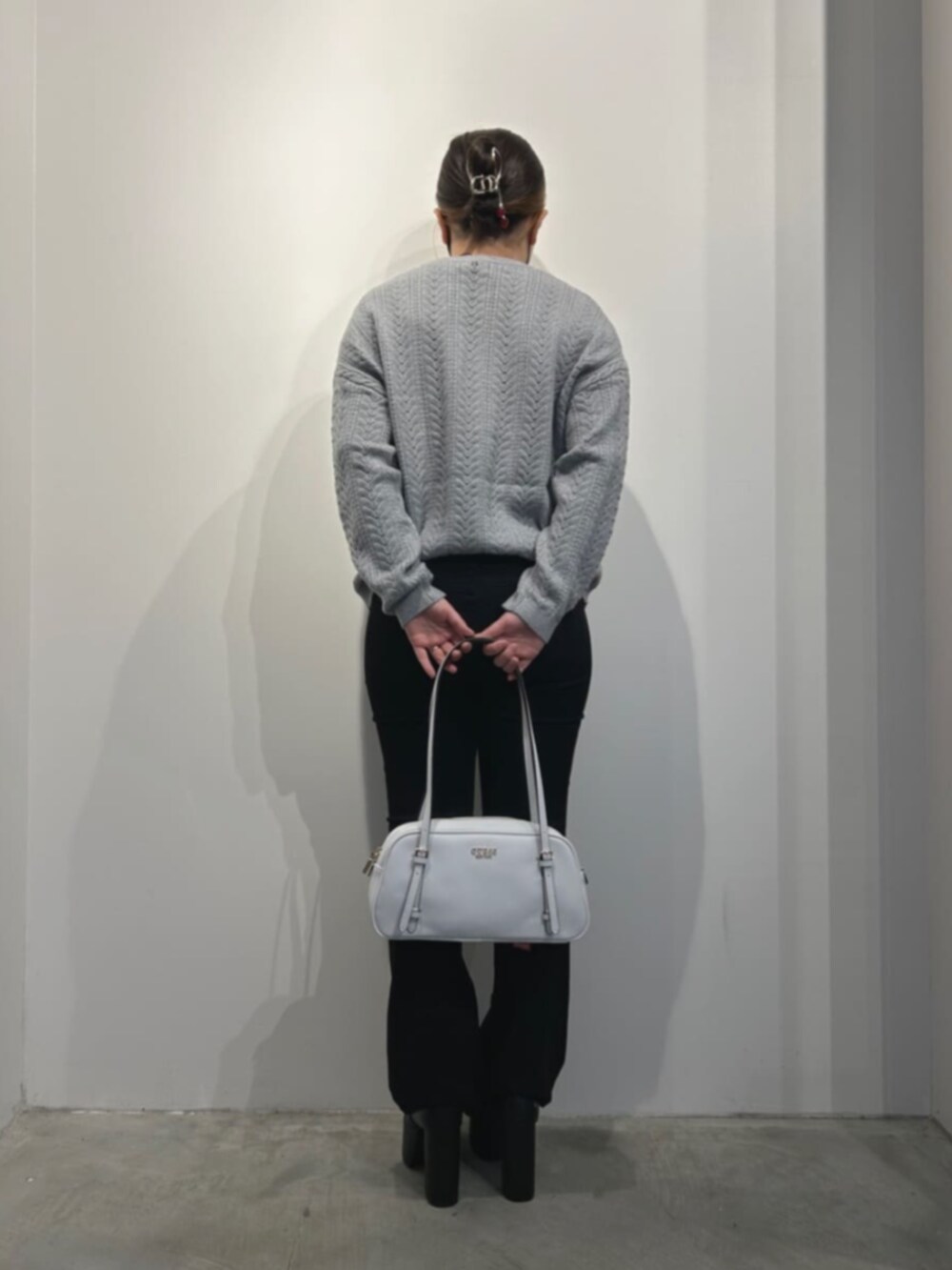 ホワイト系のショルダーバッグ、ブラック系のデニムパンツ、グレー系のニット/セーターを着用したレディースの冬コーディネートの2枚目の写真