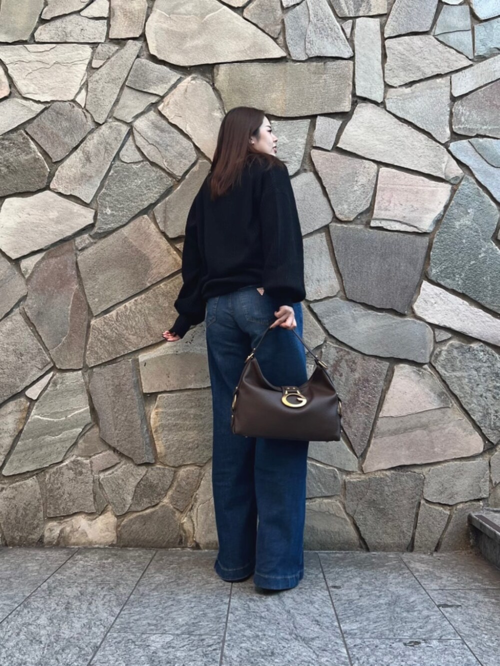 ブルー系のデニムパンツ、ホワイト系のニット/セーター、ブラウン系のショルダーバッグを着用したレディースの秋コーディネートの2枚目の写真