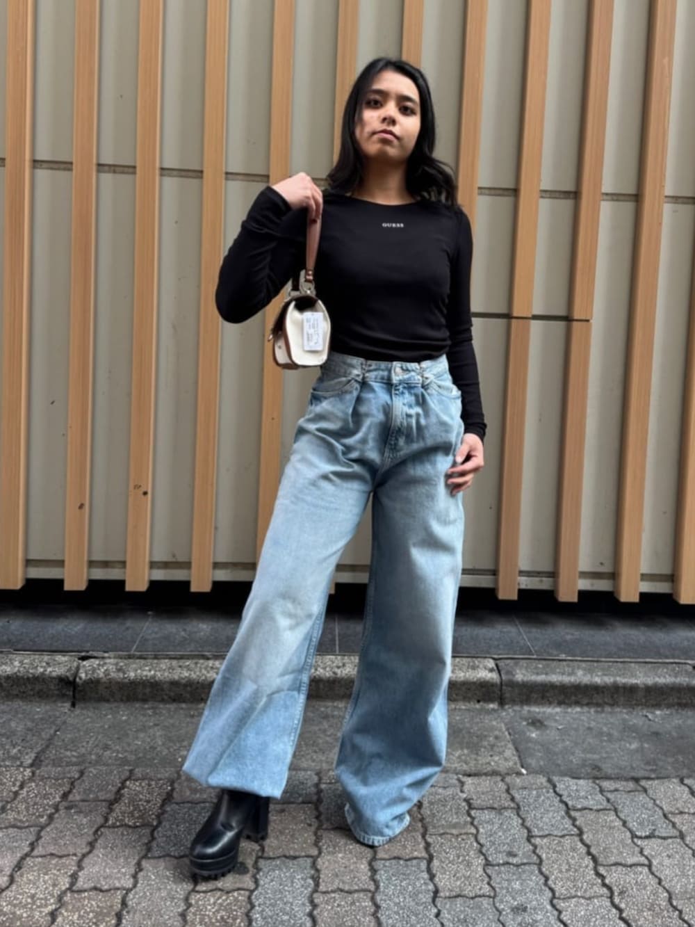 ブルー系のデニムパンツ、ブラック系のTシャツ/カットソー、イエロー系のショルダーバッグを着用したレディースの春コーディネートの2枚目の写真