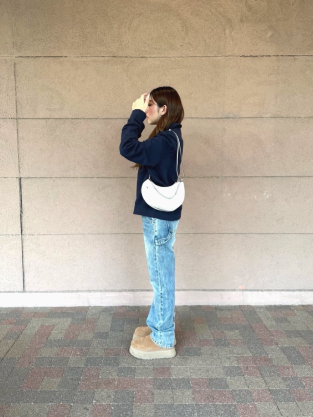 ブルー系のデニムパンツ、ホワイト系のハンドバッグ、ブルー系のスウェットを着用したレディースの冬コーディネートの3枚目の写真