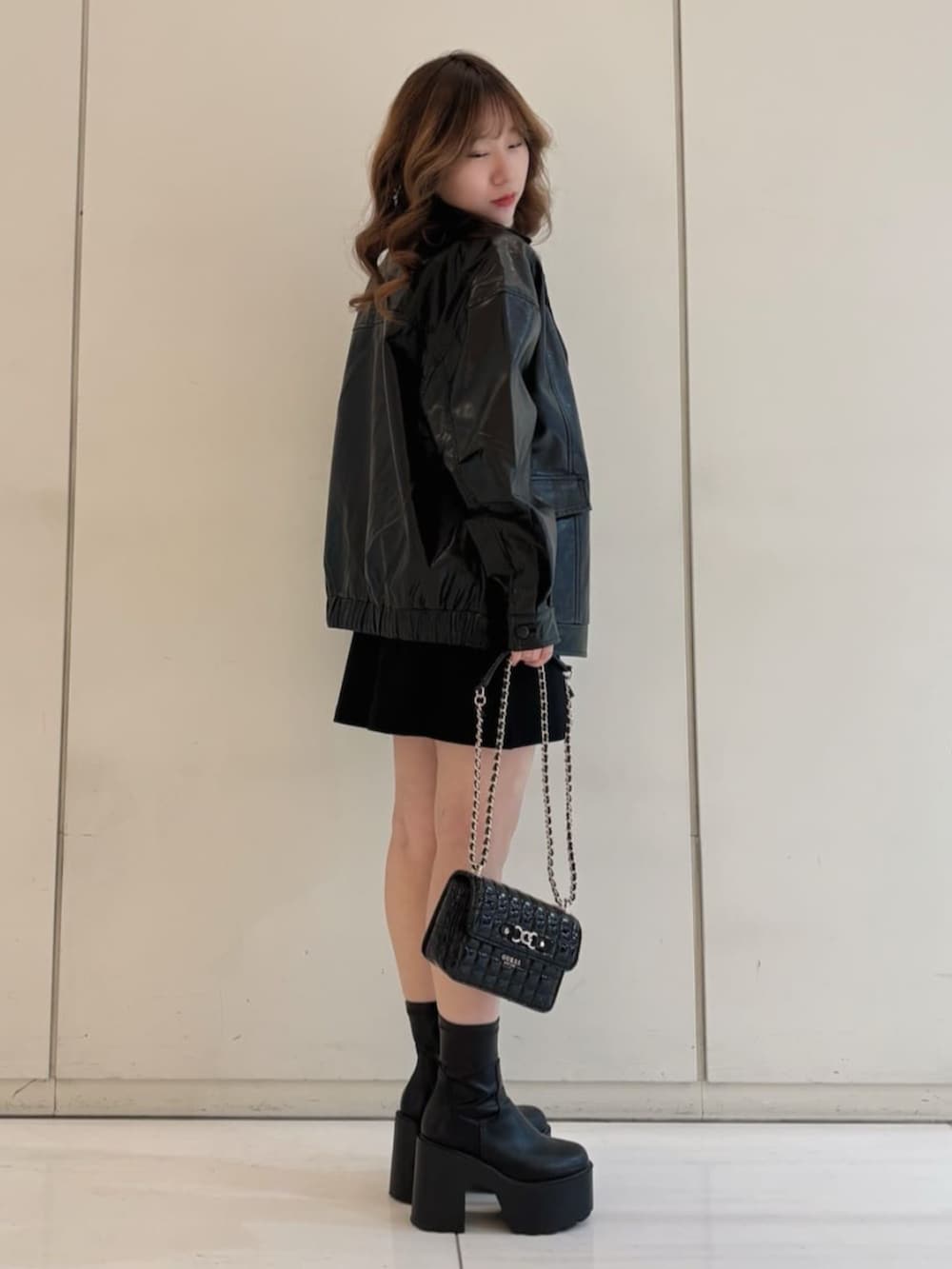 ホワイト系のニット/セーター、ブラック系のスカート、ブラック系のカバーオールを着用したレディースの冬コーディネートの3枚目の写真