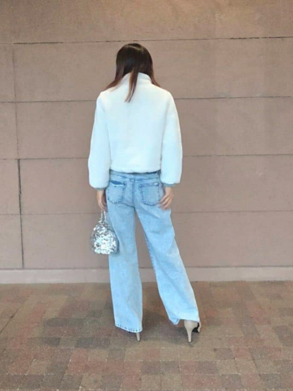 シルバー系のショルダーバッグ、ブルー系のデニムパンツ、ホワイト系のブルゾンを着用したレディースの冬コーディネートの2枚目の写真