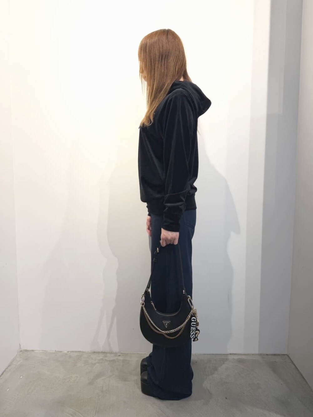 ブラック系のショルダーバッグ、ブルー系のデニムパンツ、ブラック系のパーカーを着用したレディースの春コーディネートの3枚目の写真