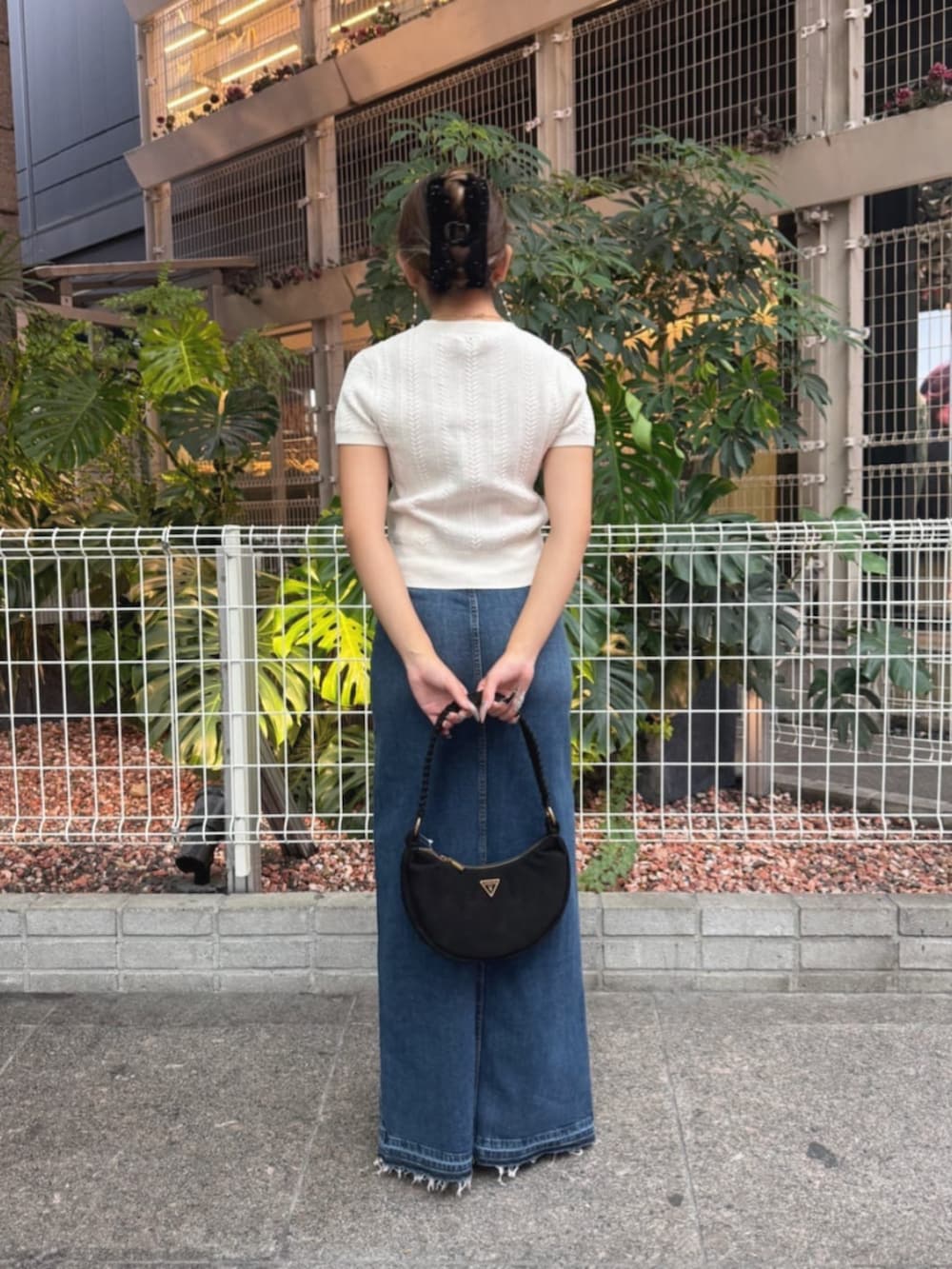 ブルー系のデニムスカート、ホワイト系のニット/セーター、ブラック系のショルダーバッグを着用したレディースの秋コーディネートの2枚目の写真