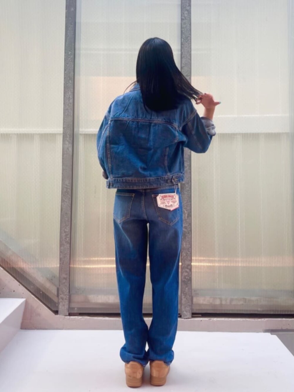 ブルー系のデニムジャケット、ブルー系のデニムパンツ、ホワイト系のインナーウェア/肌着を着用したレディースの秋コーディネートの2枚目の写真