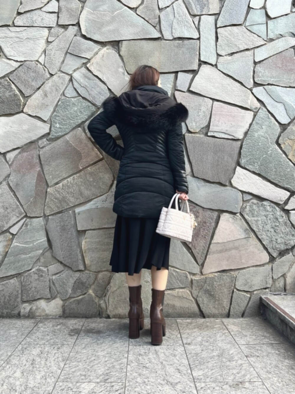 ブラック系のワンピース、ホワイト系のショルダーバッグ、ブラック系のダウンジャケット/コートを着用したレディースの秋コーディネートの2枚目の写真