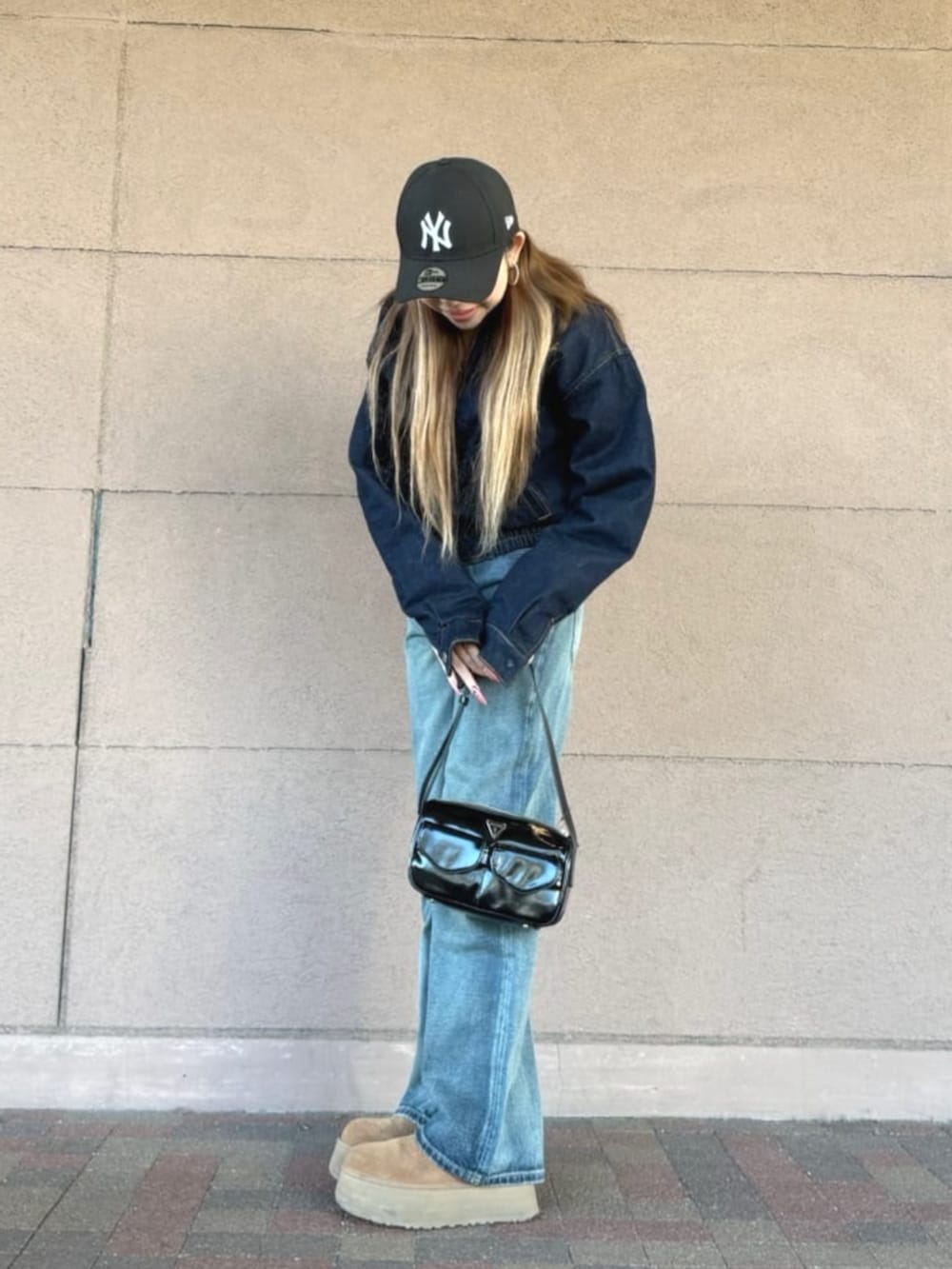 ブルー系のデニムジャケット、ブラック系のショルダーバッグ、ブルー系のデニムパンツを着用したレディースの春コーディネートの2枚目の写真