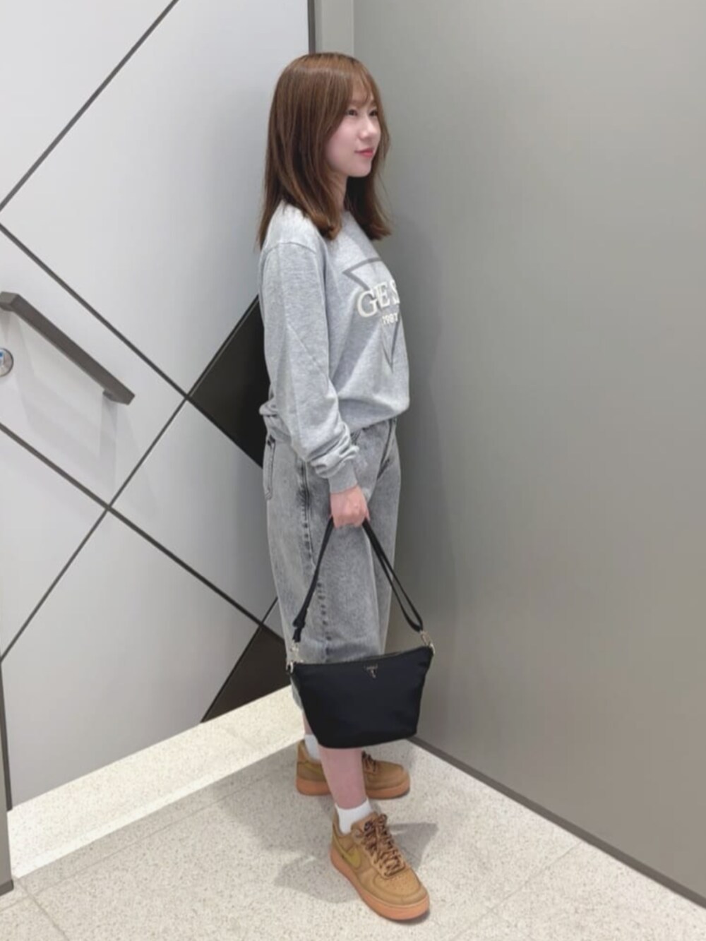 ブラック系のハンドバッグ、グレー系のデニムパンツ、グレー系のニット/セーターを着用したレディースの夏コーディネートの3枚目の写真