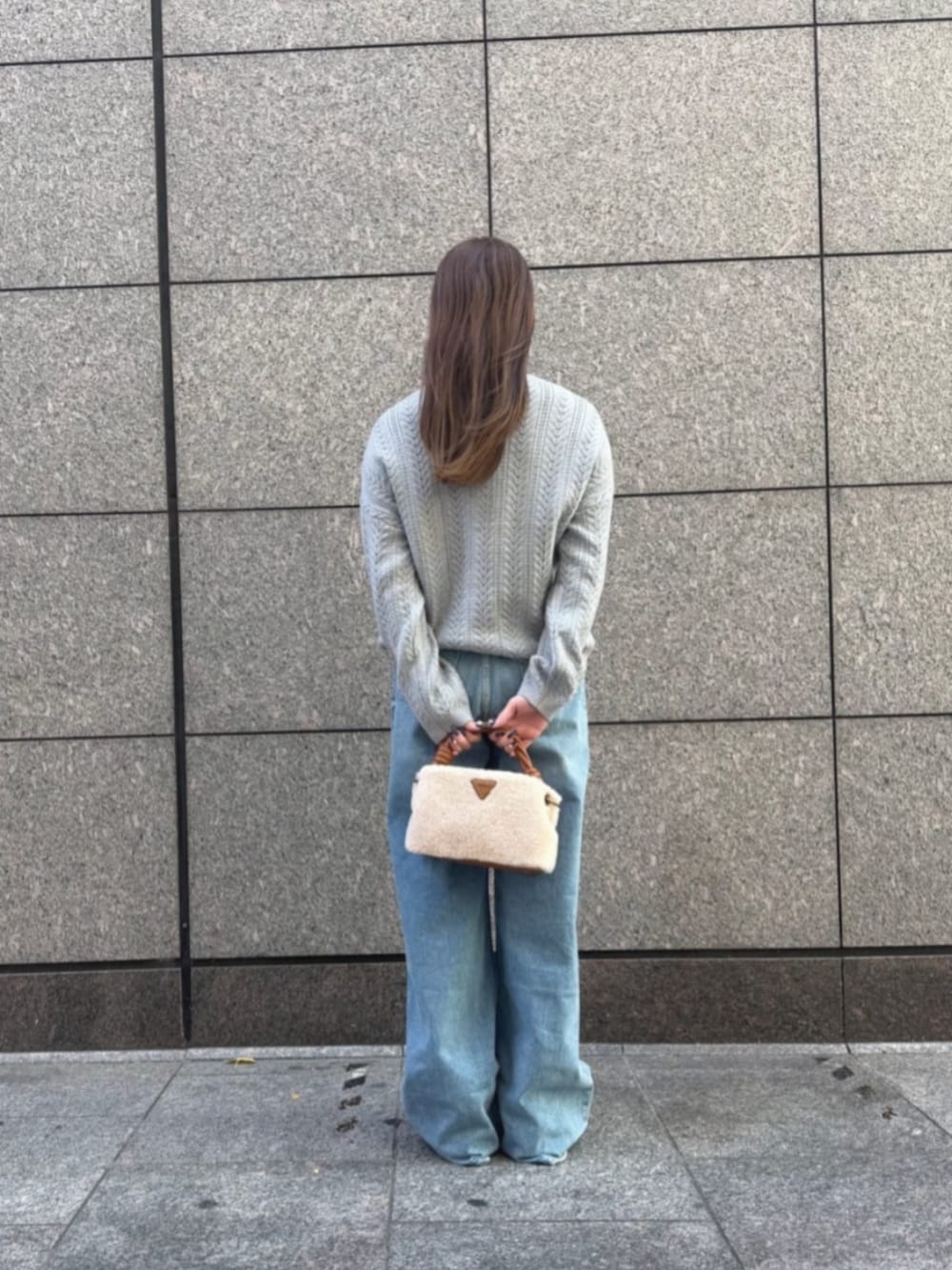 イエロー系のショルダーバッグ、グレー系のニット/セーター、ブルー系のデニムパンツを着用したレディースの冬コーディネートの2枚目の写真