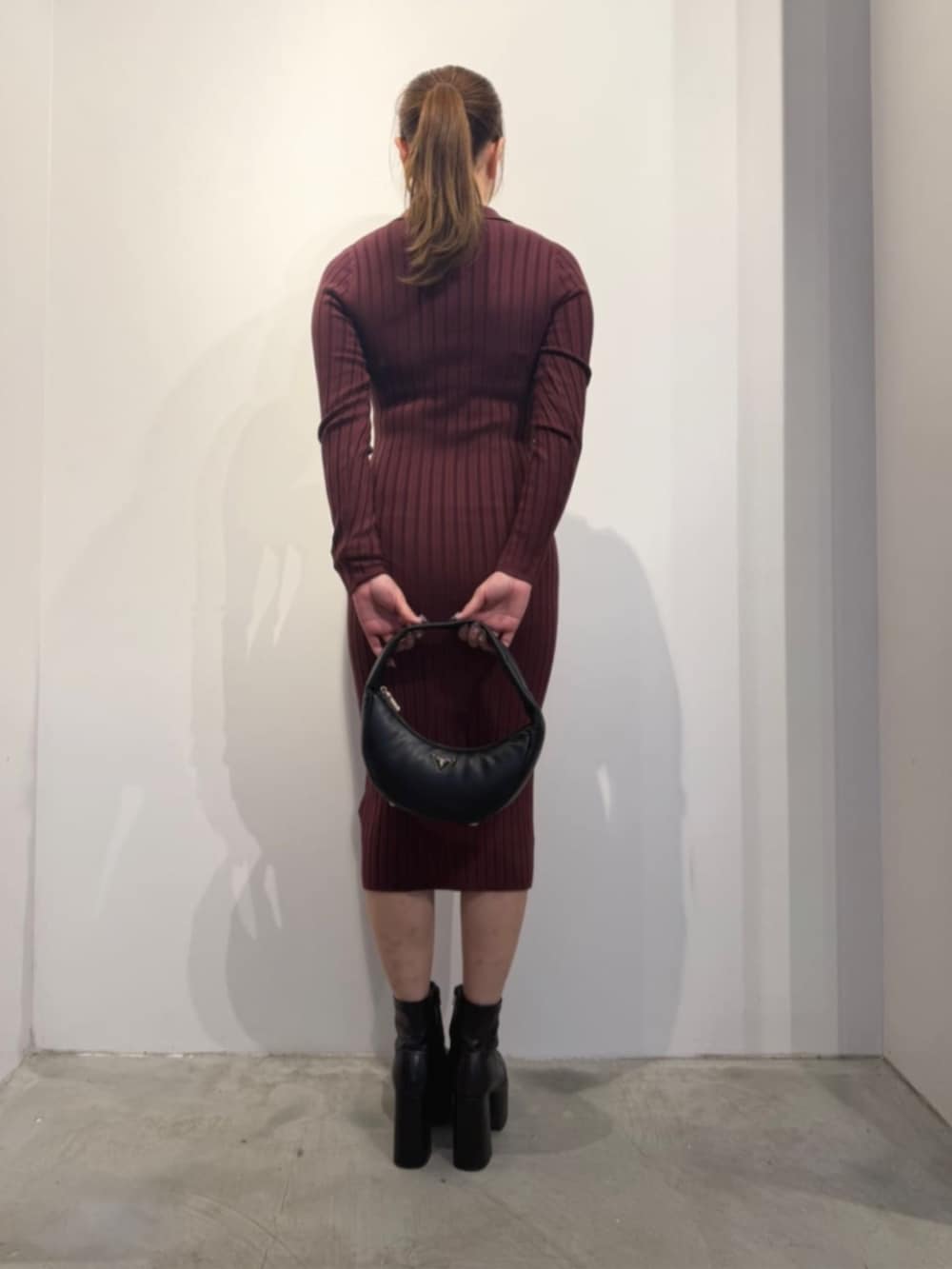 ブラック系のショルダーバッグ、レッド系のワンピースを着用したレディースの冬コーディネートの2枚目の写真