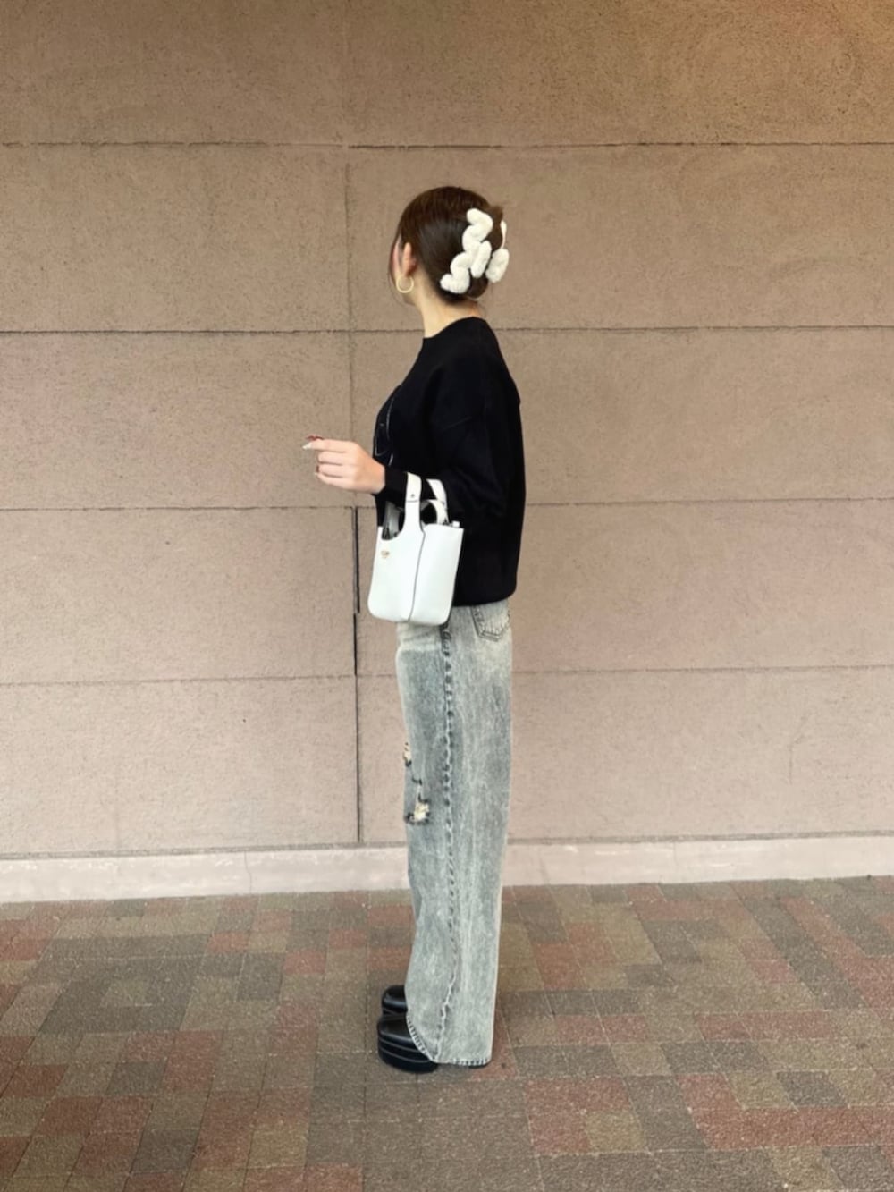 ホワイト系のショルダーバッグ、グレー系のデニムパンツ、ブラック系のニット/セーターを着用したレディースの冬コーディネートの3枚目の写真