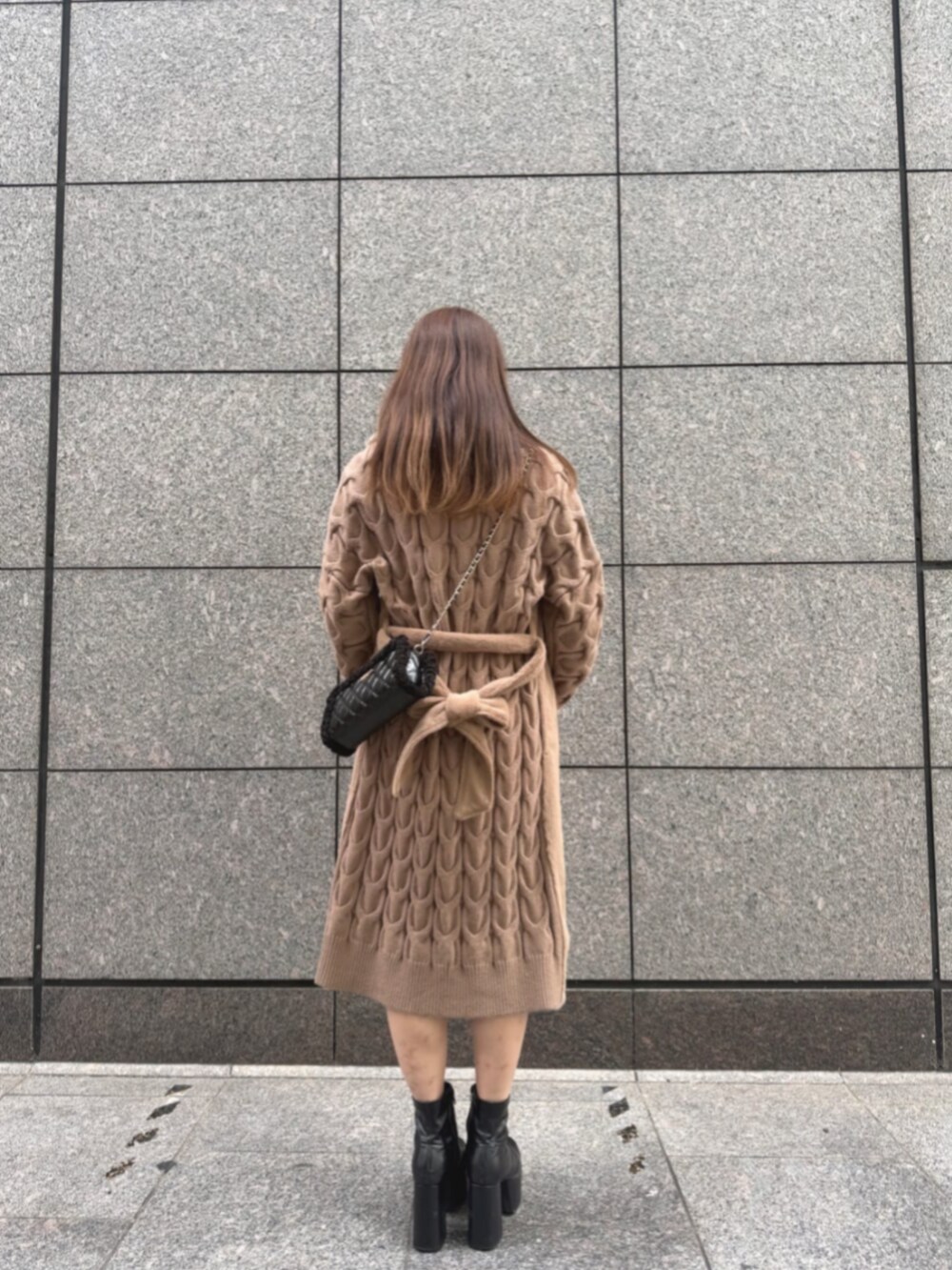 ベージュ系のムートンコート、ブラック系のショルダーバッグ、ホワイト系のワンピースを着用したレディースの冬コーディネートの2枚目の写真