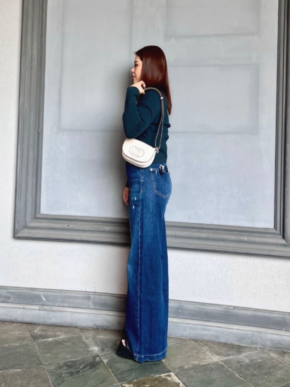 ブルー系のデニムパンツ、ホワイト系のタンクトップ、ホワイト系のショルダーバッグを着用したレディースの秋コーディネートの3枚目の写真