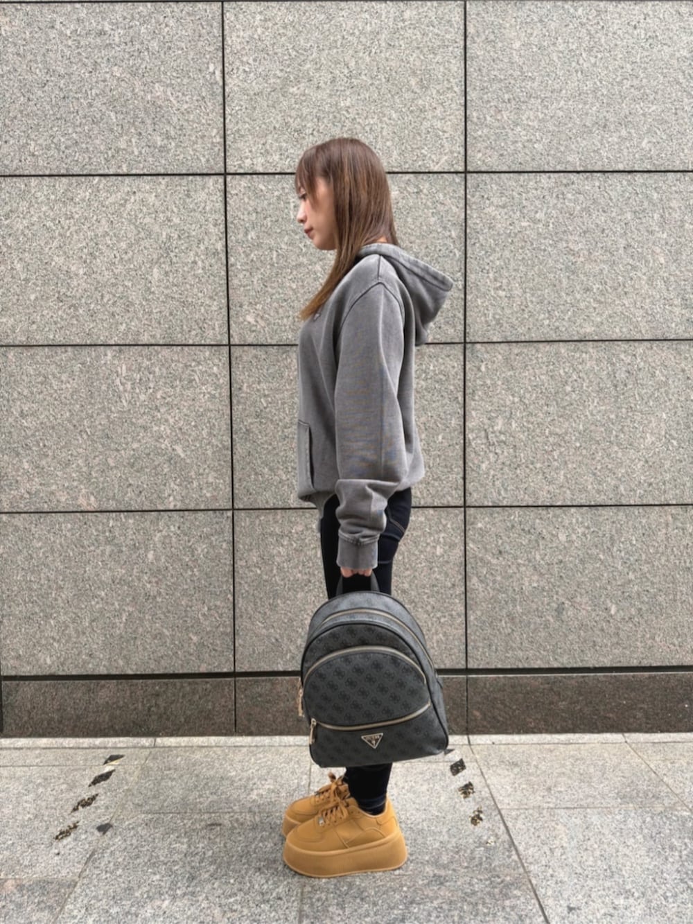 ブルー系のデニムパンツ、グレー系のバックパック/リュック、グレー系のパーカーを着用したレディースの秋コーディネートの3枚目の写真