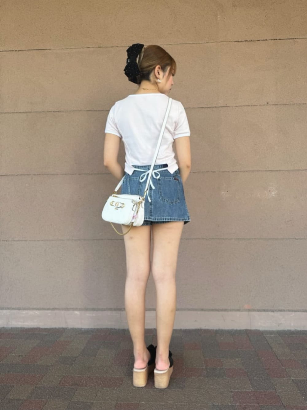 ホワイト系のショルダーバッグ、ブルー系のデニムパンツ、ピンク系のTシャツ/カットソーを着用したレディースの秋コーディネートの2枚目の写真