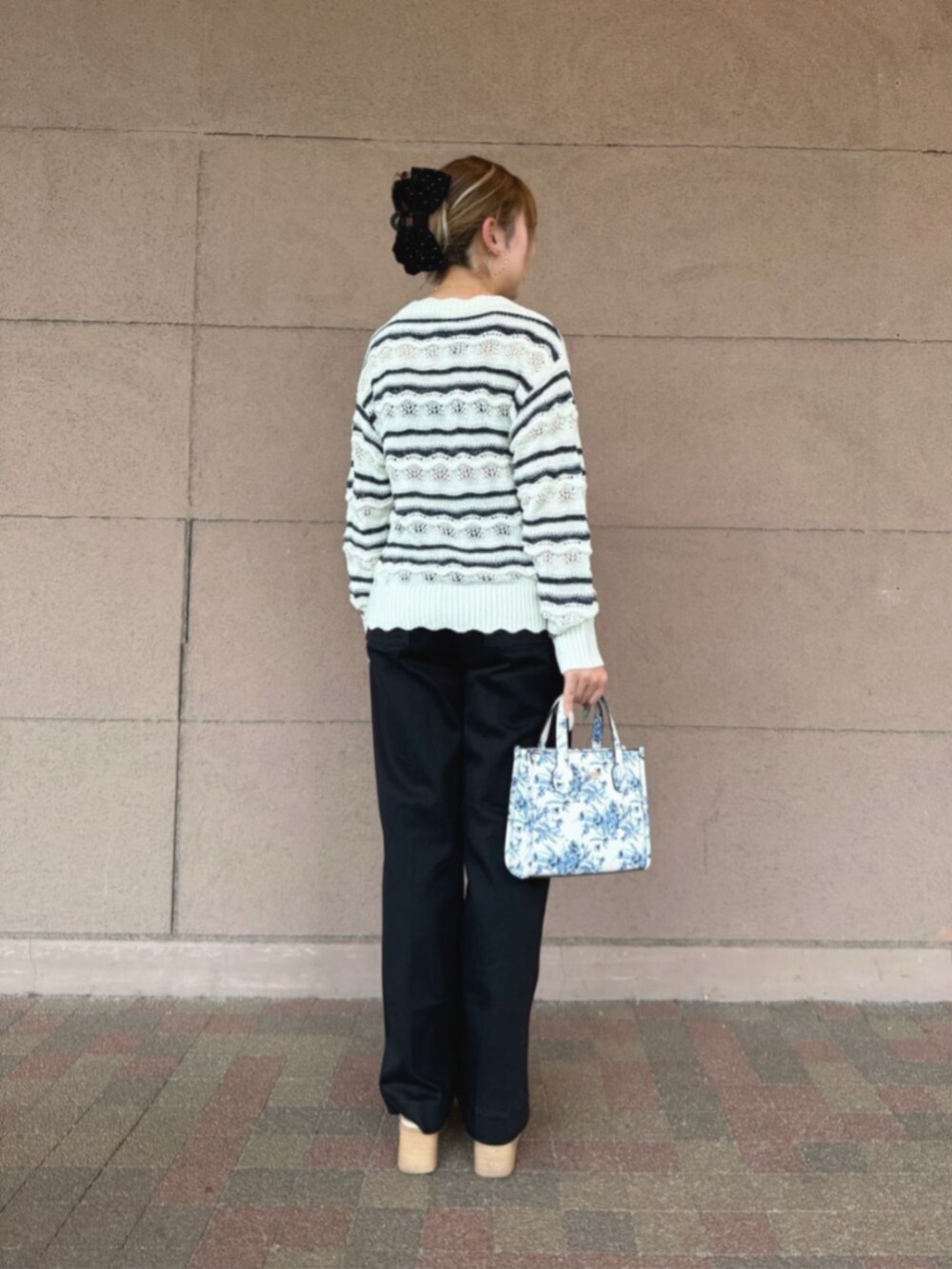 ブラック系のデニムパンツ、ホワイト系のショルダーバッグ、ホワイト系のニット/セーターを着用したレディースの秋コーディネートの2枚目の写真